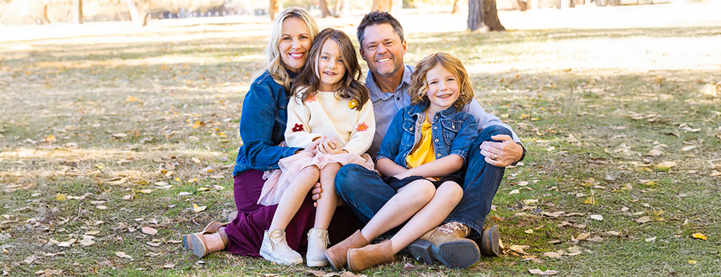 Image of Justin Osmond and wife and daughters sitting in the grass